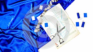 Fashion designer`s workplace. sewing business. Blue satin or silk fabric with sewing accessories, pattern, scissors, tape measure