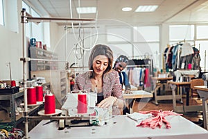 Fashion designer using sewing machine in her workshop