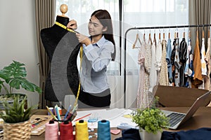 Fashion designer women use measure tape to measuring size and checking details clothes on mannequin