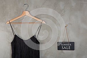 Fashion discount concept - blackboard with text Summer Sale and beautiful little black dress on a hanger