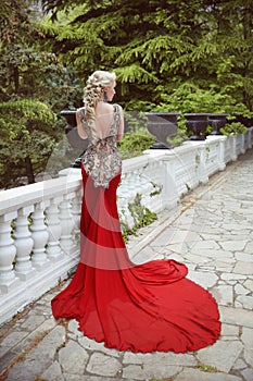 Fashion elegant blond woman model in red gown with long train of