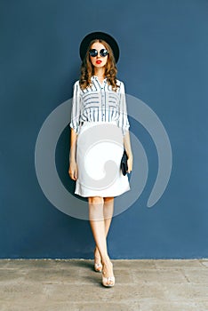 Fashion elegant woman in a black round hat, white skirt