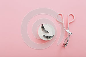 Fashion fake false eyelash with curler on pink background, top view