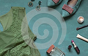 Fashion flat lay on the wooden turquoise background with cosmetics, shoes and dress. Top view concept frame.