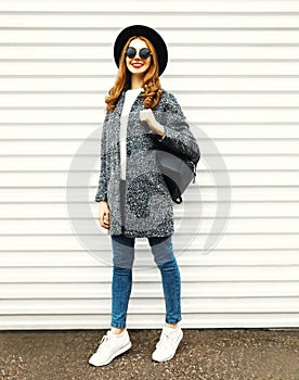 Fashion full-length woman in gray coat, black round hat posing