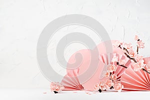 Fashion gentle floral spring pastel background - branch pink sakura flowers, circles, paper fans in white interior as stage.