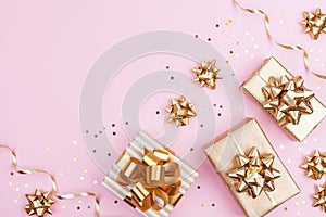 Fashion gifts or presents boxes with golden bows and star confetti on pink pastel background top view. Flat lay for Christmas