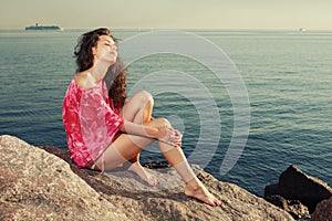 Fashion girl on the beach on rocks against the background of the