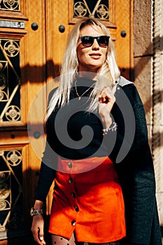 Fashion Girl In Fashionable Clothing. Beautiful girl in a coat and a red skirt. Posing In Street