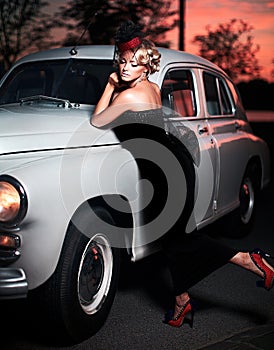 Fashion girl in retro style posing near old car