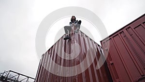 Fashion girl sits on a freight container