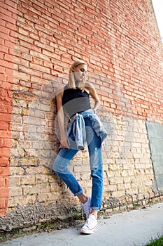 fashion girl standing near brick wall in denim and sneakers. Vogue Style