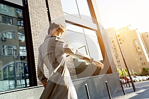 Fashion girl wear stylish trench coat walking on city street looking at camera.