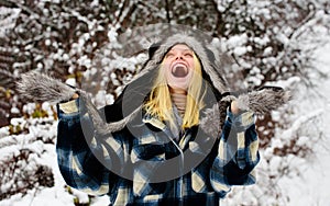 Fashion girl in wintertime. Cold winter weather. Happy beautiful woman in snowy winter park in warm clothes. Smiling