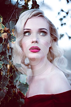 Fashion gorgeous young blonde woman in beautiful red dress in a fairy-tale forest. magic atmosphere. Retouched toning shot