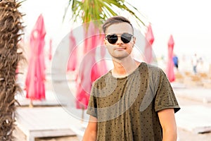 Fashion guy on the beach walking in sunglasses