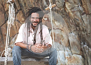 Fashion guy with dreadlocks in tropical coconut palms smiling