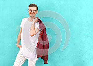 Fashion guy in glasses poses near the wall the color of the sour