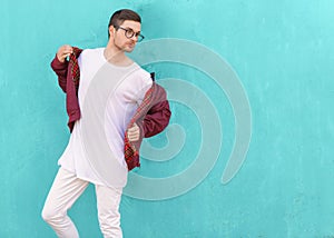 Fashion guy in glasses poses near the wall the color of the sour