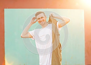 Fashion guy in glasses poses near the wall the color of the sour