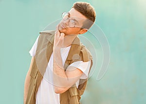 Fashion guy in glasses poses near the wall the color of the sour