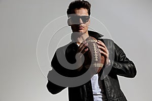 fashion guy in leather jacket playing football and throwing pigskin ball