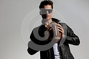 fashion guy in leather jacket playing football and throwing pigskin ball photo
