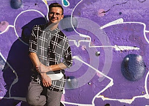 Fashion guy posing on a violet background in bright clothes