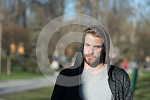 Fashion guy in stylish sportswear. Macho with beard in hood on sunny day. Bearded man wear casual sweatshirt outdoor. Lifestyle fo