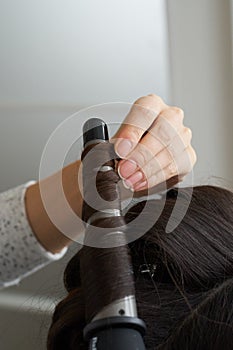 Fashion hairdresser doing hairstyle to young woman client making perm professional styler for curl.