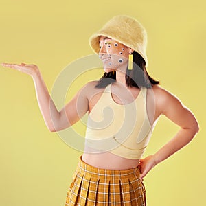 Fashion, hand and Asian woman with comic eyes isolated on a yellow background in a studio. Happy, funny and stylish girl