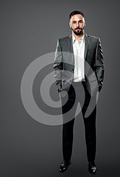 Fashion Handsome Bearded Man in Gray Suit and White Shirt without Tie. Elegant Businessman in Open Collar Shirt, Hands in Pocket