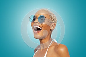 Fashion Happy laughing woman portrait wearing blue polarized sunglasses, isolated on turquoise bright background. Advertisement