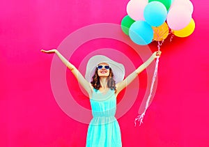 Fashion happy smiling woman with an air colorful balloons is having fun in summer over a pink background