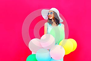 Fashion happy smiling young woman with an air colorful balloons is having fun on pink background