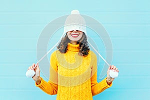 Fashion happy young woman in knitted hat and sweater having fun over colorful blue