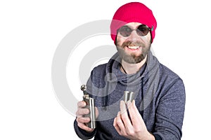 Fashion hipster cool man in sunglasses and colorful clothes pours himself a drink from a metal flask. offering drink