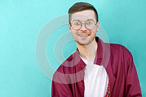 Fashion hipster guy in glasses poses near the wall the color of