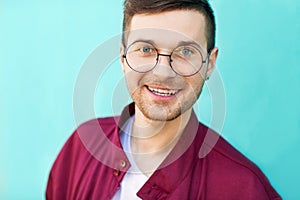 Fashion guy in glasses poses near the wall the color of the sour