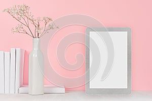 Fashion home interior with silver touch tablet with blank screen and dry flowers in ceramic vase, books on soft pink background.