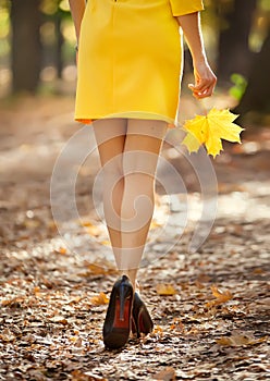 Fashion image of perfect long slim woman legs on autumn road.