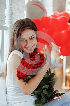 Fashion interior photo of beautiful smiling woman with dark hair holding a big bouquet of red roses in Valentine`s day