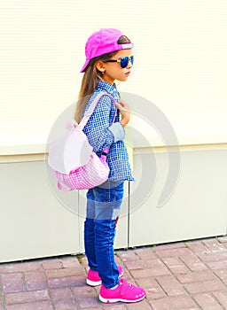 Fashion kid little girl wearing a baseball cap and backpack