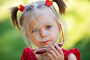 Fashion kids girl in sunglasses. adorable toddler child in mirror sunglasses, dressed in a red dress.