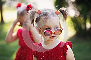 Fashion kids girl in sunglasses. adorable toddler child in mirror sunglasses, dressed in a red dress. looking away