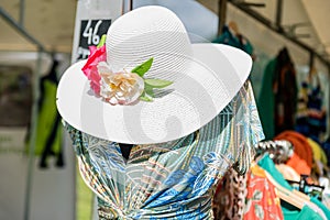 Fashion ladies blue and green dress and white hat on mannequin out in the sun