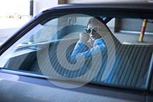 Fashion lady driving a car in a blue suit. Stylish girl sitting in the car and lying on the steering whee