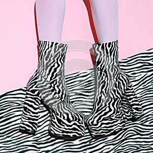 Fashion legs in heel party zebra boots on  minimal pink background. Animal texture print. Stylish tropical concept