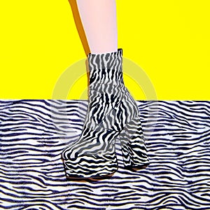Fashion legs in heel party zebra print boots on yellow minimal background. Animal texture design. Stylish tropical concept