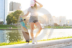 Fashion lifestyle, Beautiful young woman with skateboard, backlit at sunset.